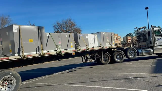 Equipment units on a flatbed trailer in a parking lot.