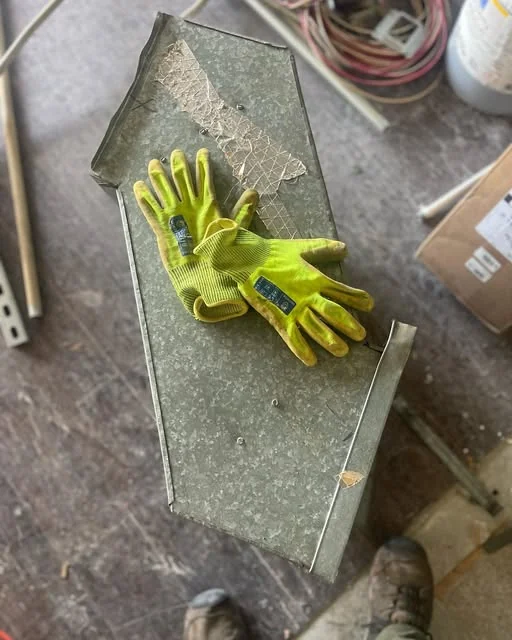 Dismantled sheet-metal duct section and work gloves.