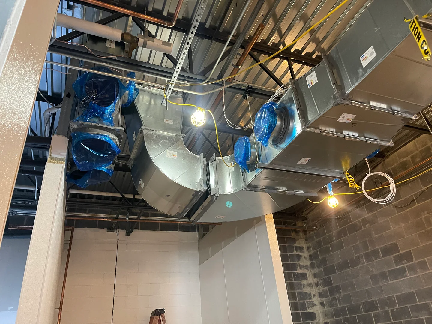 New round duct sections being installed through an unfinished interior ceiling.